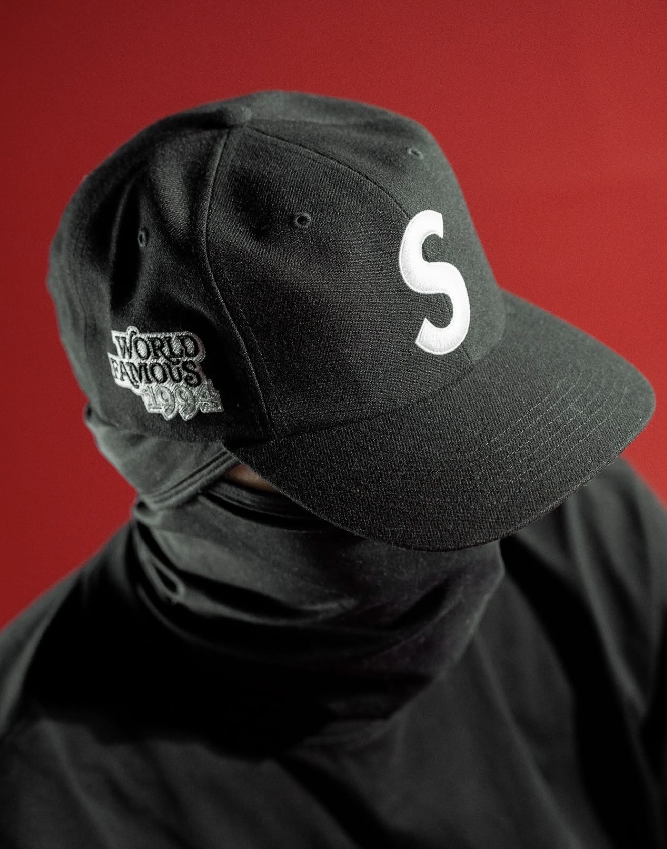 Gorra negra Supreme World Famous 1994 sobre fondo rojo — Holy Grail