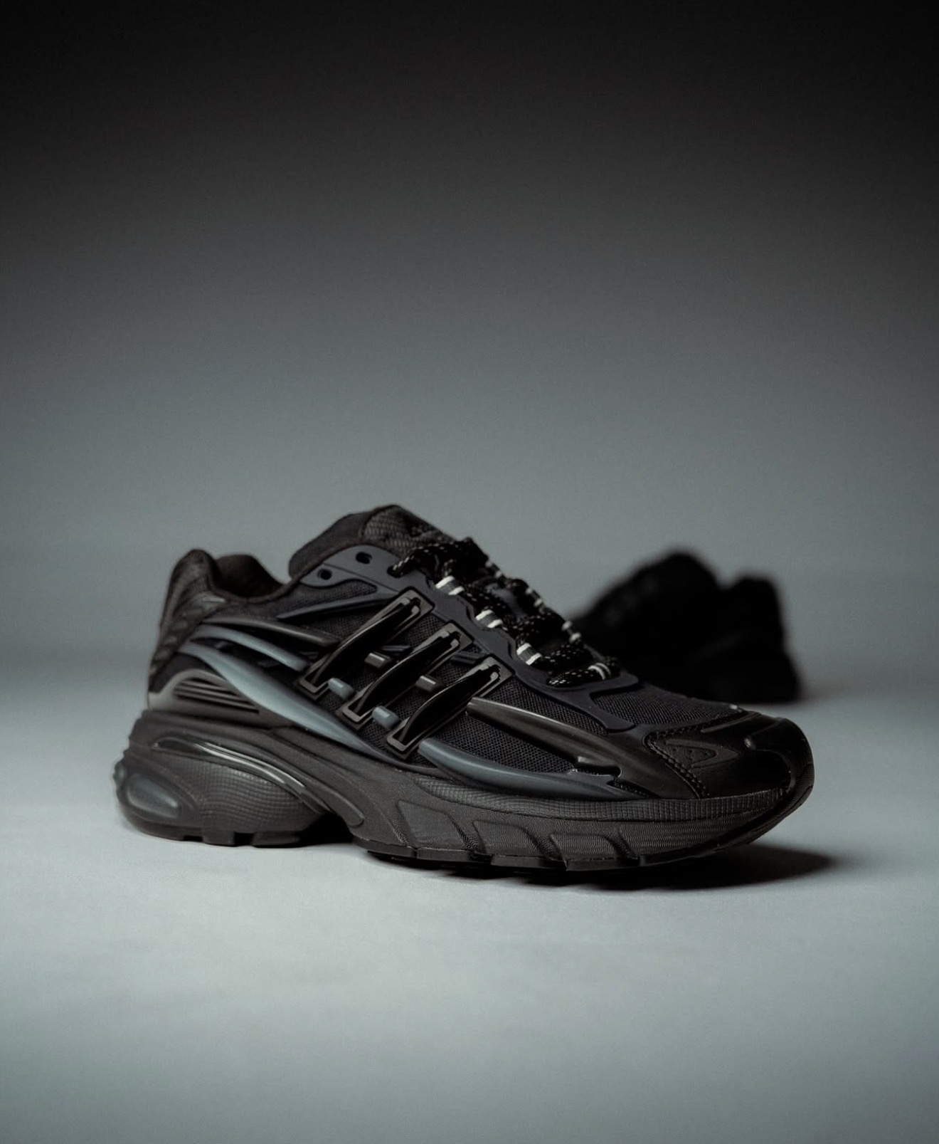 Zapatilla adidas totalmente negra fotografiada en luz de estudio — Holy Grail
